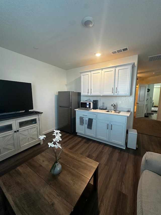 1905 George Ave, Sanger, CA 93657 - kitchen with freestanding refrigerator, black microwave, dark wood-style floors, white cabinets, and light countertops