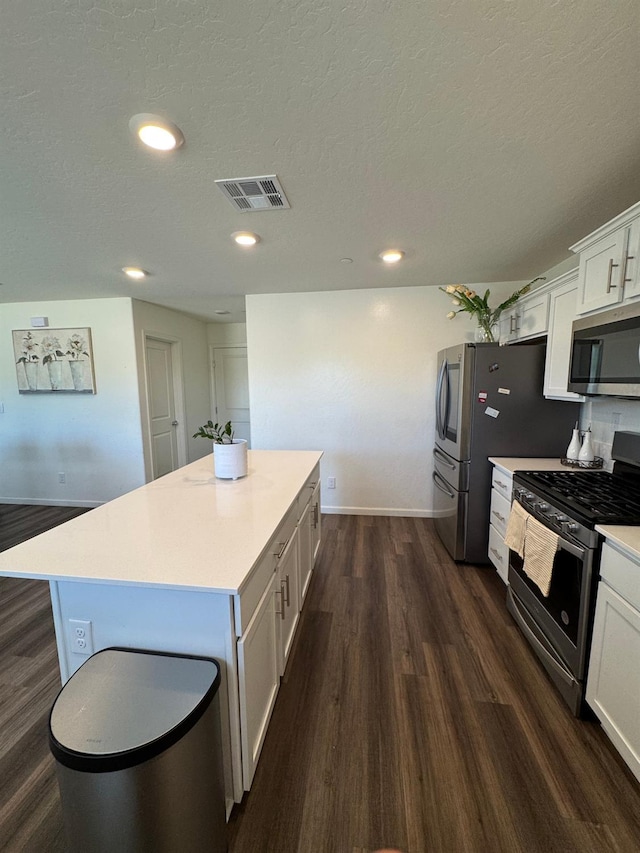 1905 George Ave, Sanger, CA 93657 - kitchen featuring appliances with stainless steel finishes, a center island, dark wood finished floors, white cabinetry, and light countertops