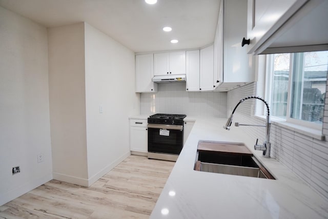 1530 E Home Ave, Fresno, CA 93728 - kitchen with stainless steel range with gas stovetop, under cabinet range hood, backsplash, light wood-style floors, and light countertops