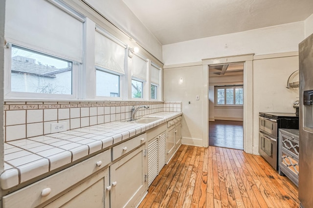 3303 E Mono Ave, Fresno, CA 93702 - kitchen featuring tile counters, light wood-style flooring, decorative backsplash, and range with two ovens