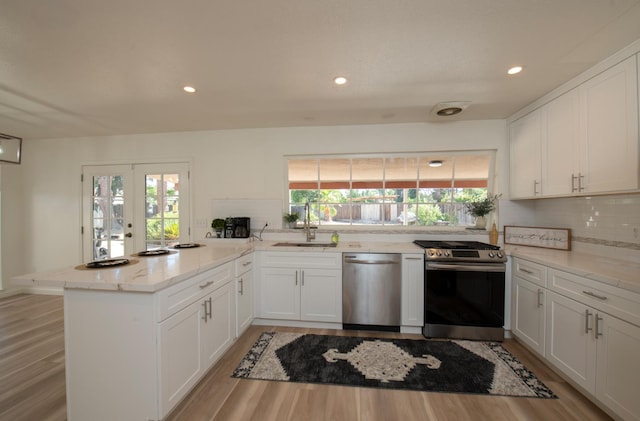 1535 S Homsy Ave, Fresno, CA 93727 - kitchen featuring stainless steel appliances, a peninsula, tasteful backsplash, white cabinetry, and light wood-style floors