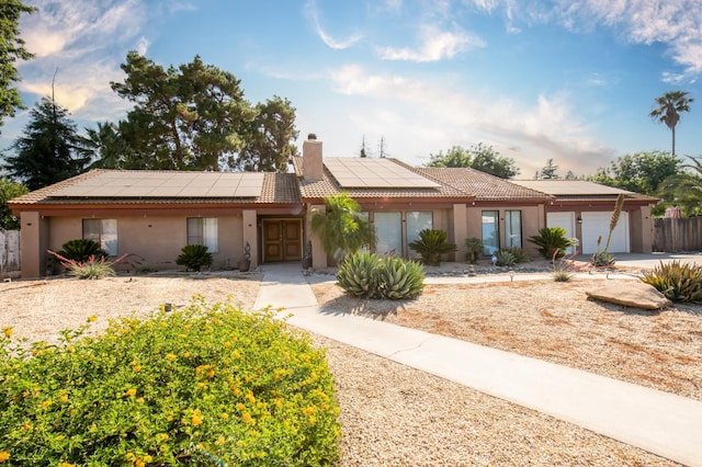 1535 S Homsy Ave, Fresno, CA 93727 - view of front of property with a chimney, stucco siding, an attached garage, and solar panels