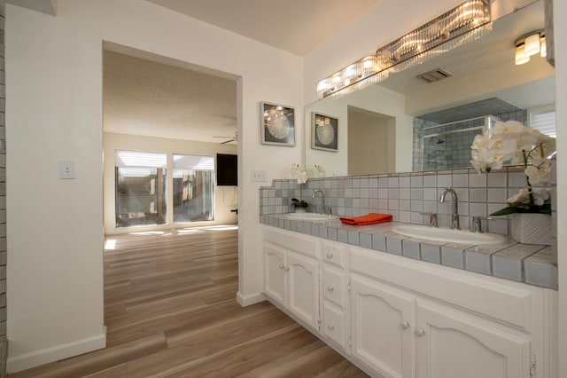 1535 S Homsy Ave, Fresno, CA 93727 - bathroom with tasteful backsplash, double vanity, wood finished floors, tiled shower, and ceiling fan