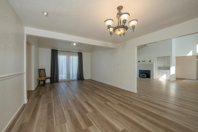 1535 S Homsy Ave, Fresno, CA 93727 - unfurnished living room featuring a chandelier, wood finished floors, a textured ceiling, and a fireplace