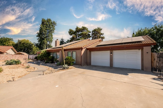 1535 S Homsy Ave, Fresno, CA 93727 - view of front of house with a chimney, driveway, roof mounted solar panels, stucco siding, and a tile roof