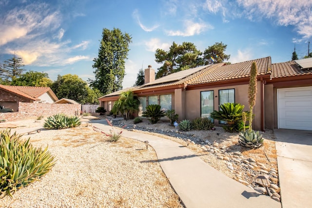 1535 S Homsy Ave, Fresno, CA 93727 - view of front of home featuring a chimney, roof mounted solar panels, stucco siding, and a tile roof
