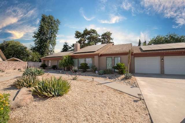 1535 S Homsy Ave, Fresno, CA 93727 - view of front of property with a chimney, roof mounted solar panels, a garage, and stucco siding