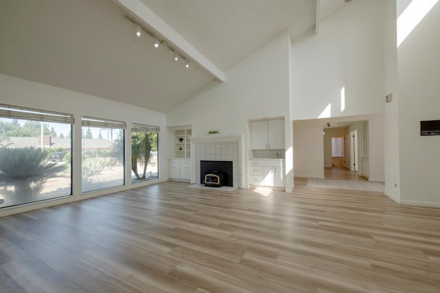 1535 S Homsy Ave, Fresno, CA 93727 - unfurnished living room with high vaulted ceiling, rail lighting, a tile fireplace, and light wood-type flooring