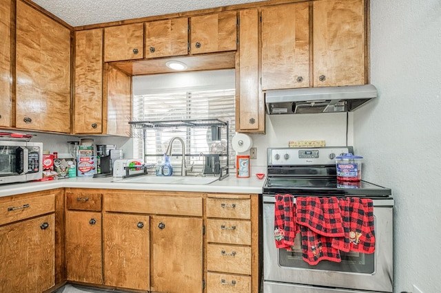 5400 Amber Ave, Clovis, CA 93619 - kitchen featuring under cabinet range hood, stainless steel appliances, light countertops, and brown cabinets