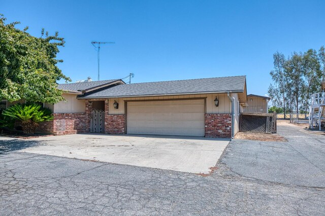5400 Amber Ave, Clovis, CA 93619 - view of front of home featuring brick siding, an attached garage, driveway, and roof with shingles