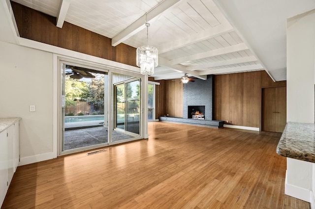 1095 W San Ramon Ave, Fresno, CA 93711 - unfurnished living room featuring a ceiling fan, beamed ceiling, a fireplace, wood finished floors, and wood walls