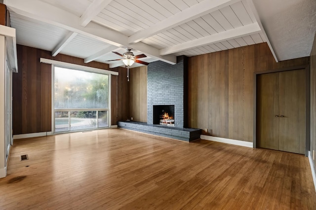 1095 W San Ramon Ave, Fresno, CA 93711 - unfurnished living room with wood finished floors, wood walls, a fireplace, beam ceiling, and ceiling fan