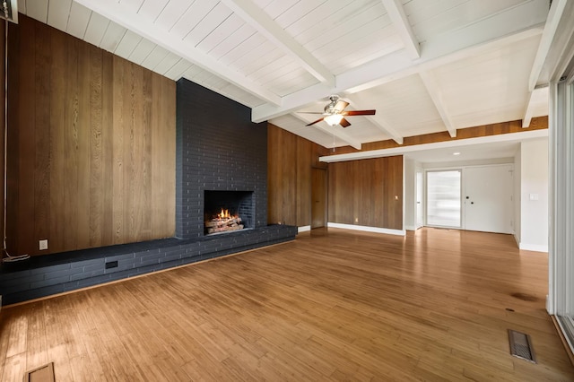 1095 W San Ramon Ave, Fresno, CA 93711 - unfurnished living room with wood walls, a brick fireplace, ceiling fan, and wood finished floors