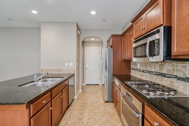 3563 Magnificent Way, Clovis, CA 93619 - kitchen with stainless steel appliances, brown cabinetry, arched walkways, tasteful backsplash, and dark stone counters