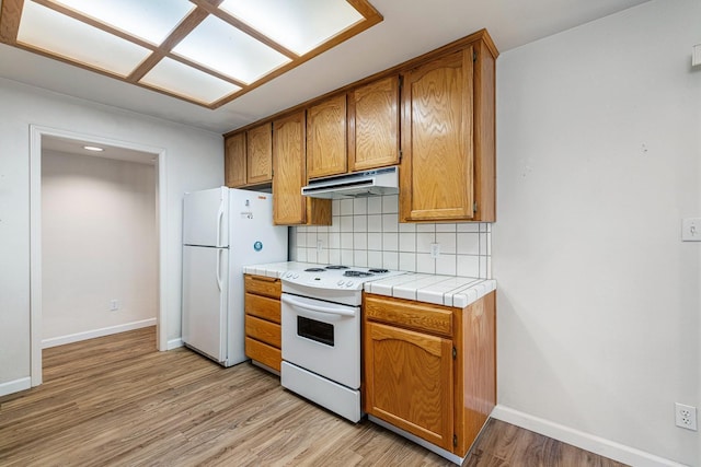 5137 W Stuart Ave, Fresno, CA 93722 - kitchen featuring white appliances, under cabinet range hood, backsplash, light wood-style flooring, and brown cabinetry