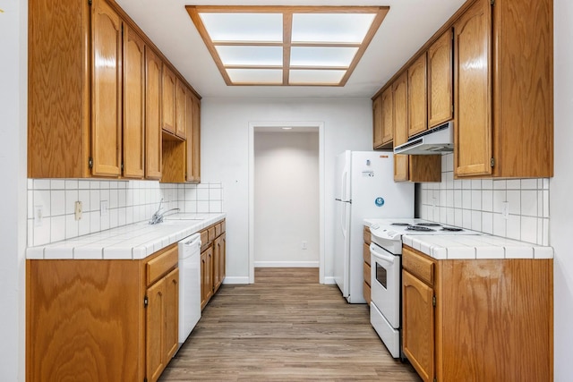 5137 W Stuart Ave, Fresno, CA 93722 - kitchen featuring white appliances, under cabinet range hood, light wood-style floors, and tasteful backsplash