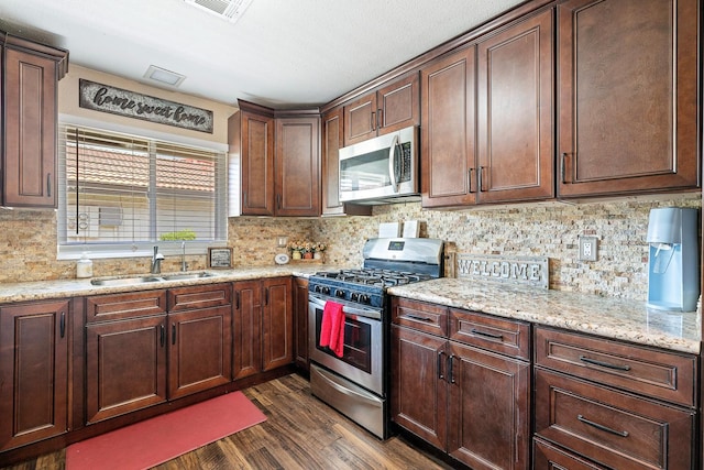 317 W Sierra Ave Unit 107, Fresno, CA 93704 - kitchen with appliances with stainless steel finishes, dark wood-type flooring, decorative backsplash, light stone countertops, and dark brown cabinetry