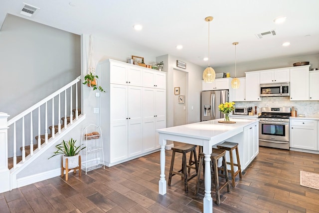 4053 Rialto Ave, Clovis, CA 93619 - kitchen featuring stainless steel appliances, dark wood-style floors, a kitchen bar, white cabinets, and recessed lighting