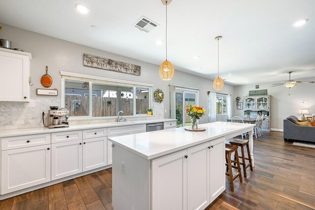 4053 Rialto Ave, Clovis, CA 93619 - kitchen featuring ceiling fan, dark wood-type flooring, white cabinetry, a kitchen bar, and stainless steel dishwasher