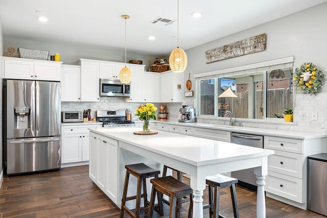 4053 Rialto Ave, Clovis, CA 93619 - kitchen featuring appliances with stainless steel finishes, backsplash, a breakfast bar, white cabinetry, and dark wood-type flooring