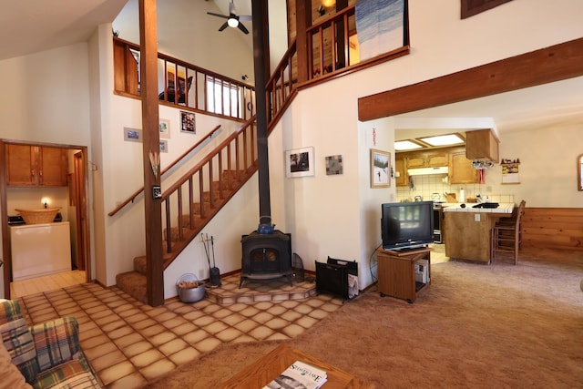 42045 Jeffrey Ln, Shaver Lake, CA 93664 - living room with stairs, ceiling fan, a wood stove, a towering ceiling, and light colored carpet