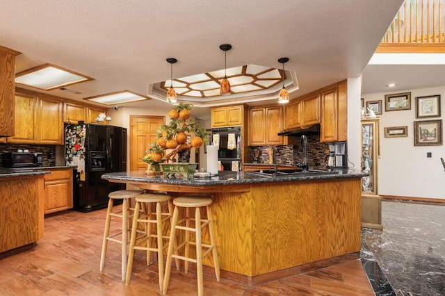 7207 E Bremer Ave, Fresno, CA 93737 - kitchen with black appliances, under cabinet range hood, decorative backsplash, and a peninsula