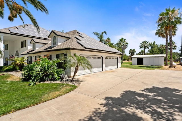 7207 E Bremer Ave, Fresno, CA 93737 - view of home's exterior with concrete driveway, a lawn, roof mounted solar panels, and stucco siding