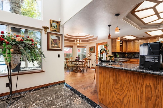 7207 E Bremer Ave, Fresno, CA 93737 - kitchen with a tray ceiling, freestanding refrigerator, brown cabinetry, marble finish flooring, and a chandelier