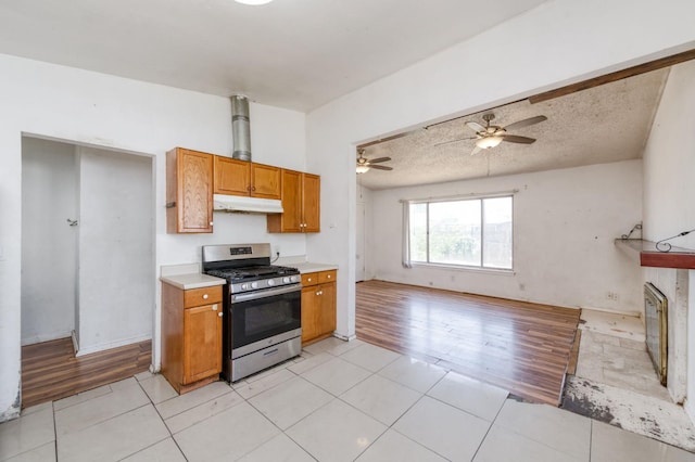 22 Beverly Dr, Clovis, CA 93612 - kitchen with stainless steel range with gas cooktop, under cabinet range hood, brown cabinets, a ceiling fan, and open floor plan