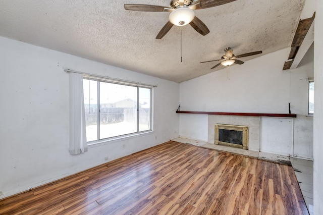22 Beverly Dr, Clovis, CA 93612 - unfurnished living room featuring wood finished floors, a ceiling fan, a textured ceiling, a tile fireplace, and lofted ceiling