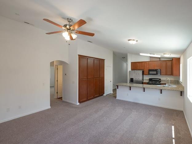 435 E San Pedro St, Merced, CA 95341 - kitchen featuring black microwave, stainless steel fridge, vaulted ceiling, a peninsula, and stove