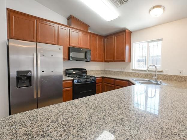 435 E San Pedro St, Merced, CA 95341 - kitchen with black appliances, light stone countertops, brown cabinetry, and lofted ceiling