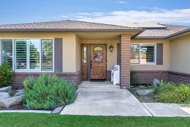 6658 N Thorne Ave, Fresno, CA 93711 - view of exterior entry with stucco siding, solar panels, and roof with shingles