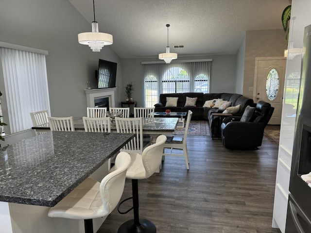 1723 Locust Ave, Clovis, CA 93611 - dining room featuring lofted ceiling, dark wood finished floors, a textured ceiling, and a fireplace