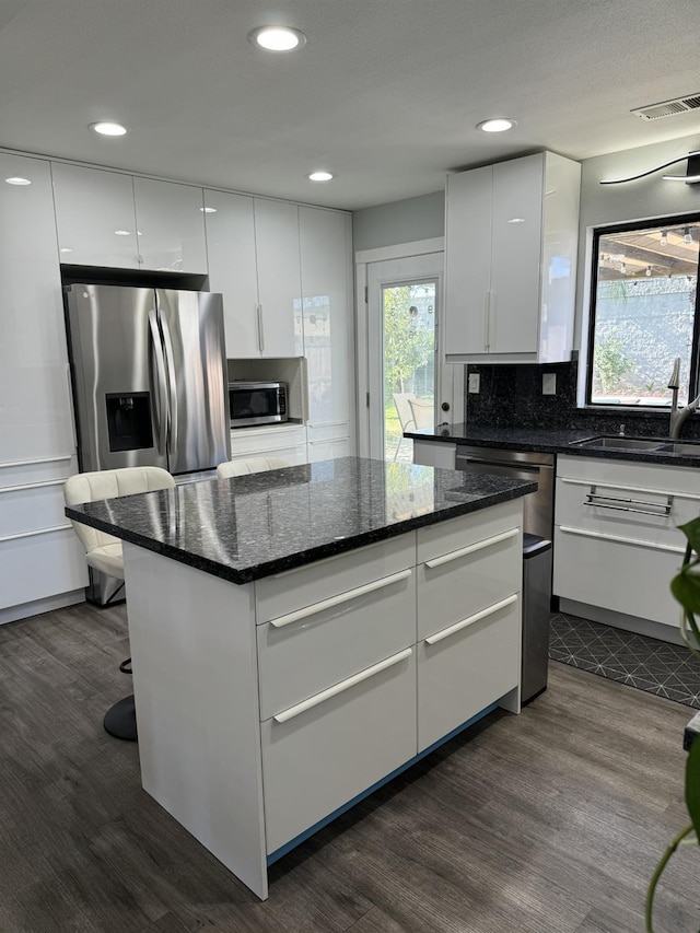1723 Locust Ave, Clovis, CA 93611 - kitchen featuring dark wood-type flooring, modern cabinets, appliances with stainless steel finishes, decorative backsplash, and white cabinetry