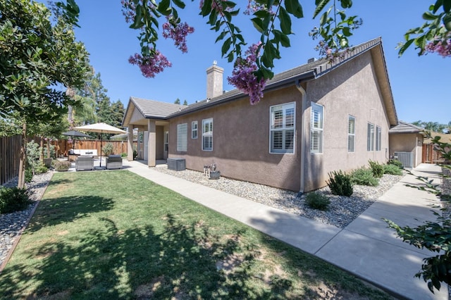 4994 W Minarets Ave, Fresno, CA 93722 - back of property featuring an outdoor hangout area, a fenced backyard, stucco siding, a chimney, and a patio area