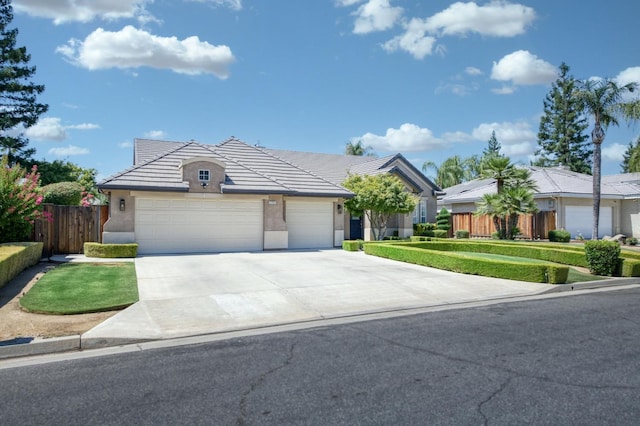4994 W Minarets Ave, Fresno, CA 93722 - view of front of house featuring stucco siding, driveway, an attached garage, and a tiled roof
