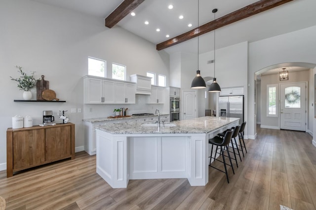 4994 W Minarets Ave, Fresno, CA 93722 - kitchen with beam ceiling, a high ceiling, arched walkways, stainless steel appliances, and white cabinets