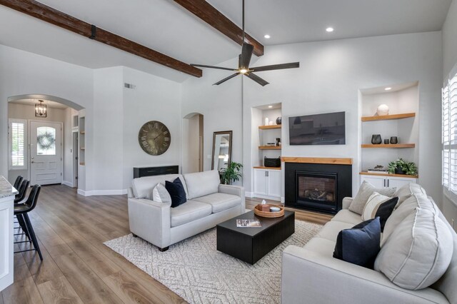 4994 W Minarets Ave, Fresno, CA 93722 - living area featuring arched walkways, a glass covered fireplace, wood finished floors, plenty of natural light, and recessed lighting