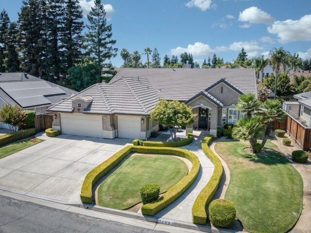 4994 W Minarets Ave, Fresno, CA 93722 - view of front of home with a tiled roof, an attached garage, concrete driveway, and stucco siding