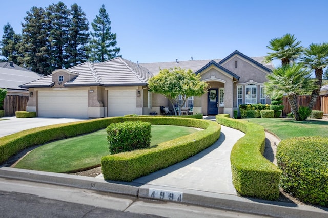 4994 W Minarets Ave, Fresno, CA 93722 - single story home with stucco siding, a tile roof, driveway, and a garage