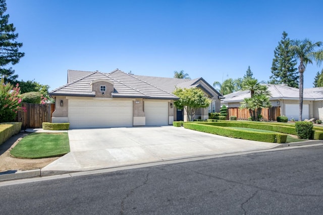 4994 W Minarets Ave, Fresno, CA 93722 - view of front of home with stucco siding, an attached garage, driveway, and a tiled roof