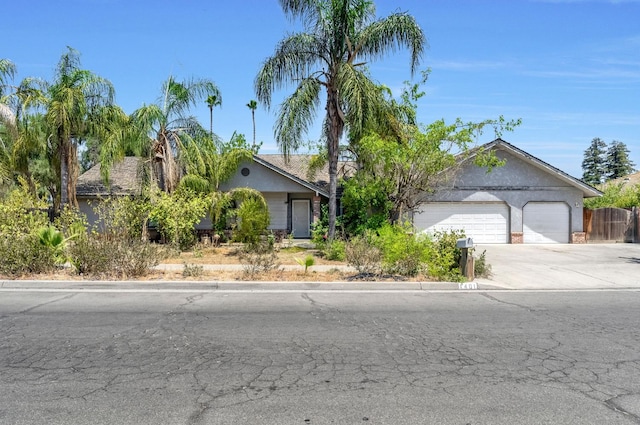 1401 S Villa Ave, Fresno, CA 93727 - view of property hidden behind natural elements with concrete driveway, an attached garage, and stucco siding