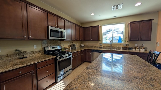 452 Rancho Mirage Rd, Madera, CA 93638 - kitchen featuring appliances with stainless steel finishes, recessed lighting, dark stone countertops, dark brown cabinetry, and light tile patterned floors