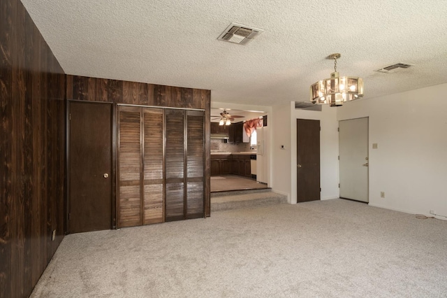 4835 E Normal Ave, Fresno, CA 93703 - unfurnished living room with a chandelier, carpet flooring, a ceiling fan, and a textured ceiling