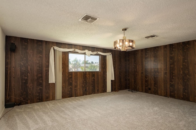 4835 E Normal Ave, Fresno, CA 93703 - spare room featuring a chandelier, wooden walls, carpet flooring, and a textured ceiling