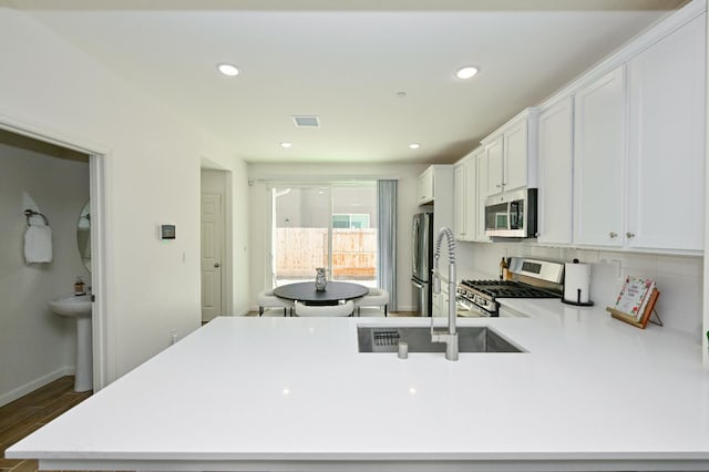 6317 E Malbec Dr, Fresno, CA 93727 - kitchen featuring appliances with stainless steel finishes, white cabinets, light countertops, a peninsula, and dark wood-style floors
