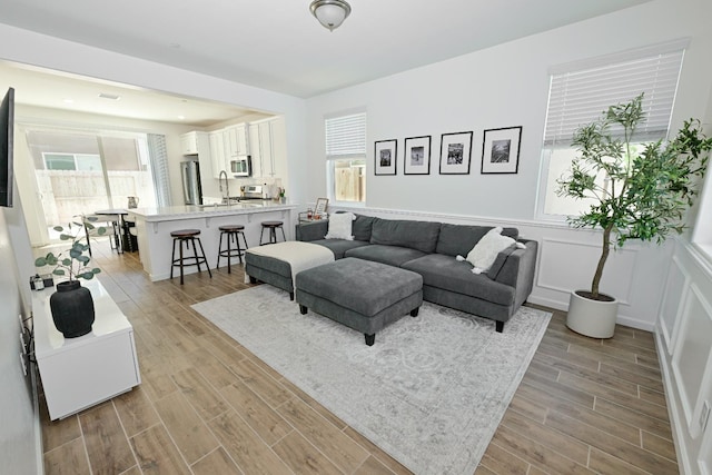 6317 E Malbec Dr, Fresno, CA 93727 - living room with healthy amount of natural light, light wood finished floors, and wainscoting