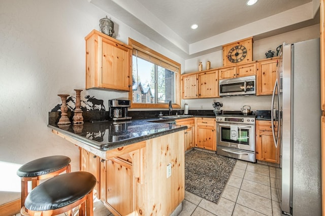 40862 Village Pass Ln, Shaver Lake, CA 93664 - kitchen with appliances with stainless steel finishes, a peninsula, recessed lighting, dark stone counters, and a kitchen bar