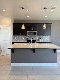 3963 Morris Ave, Clovis, CA 93619 - kitchen with stainless steel microwave, tasteful backsplash, light countertops, a breakfast bar area, and recessed lighting